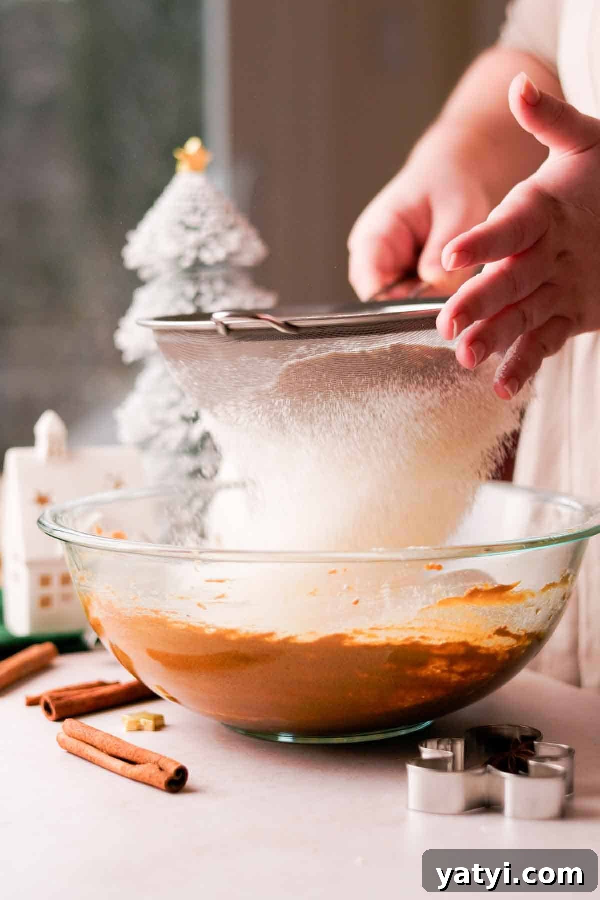 sifting flour into a bowl with a metal sieve
