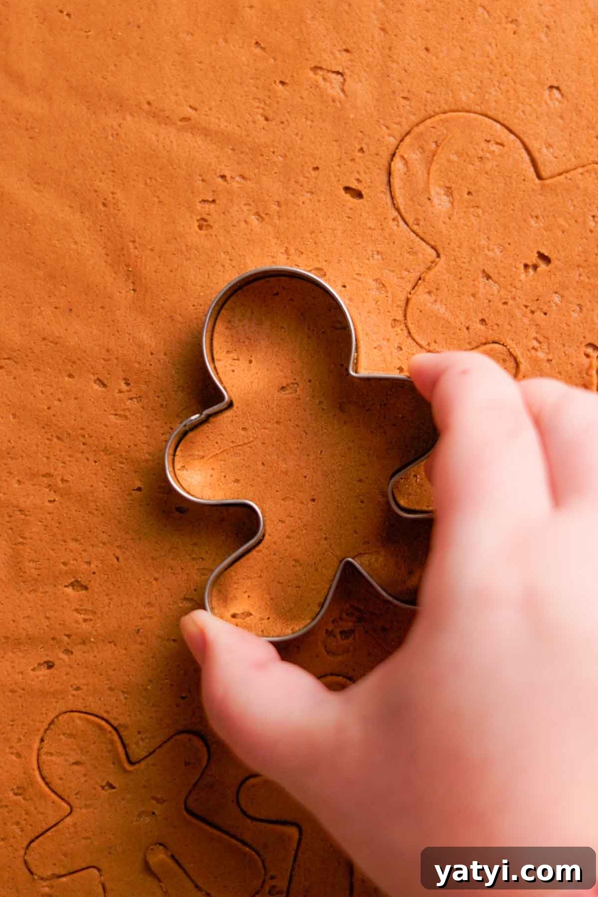 cutting out gingerbread cookie dough using gingebread men cookie cutters