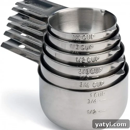 A nested stack of stainless steel measuring cups, each labeled with different measurements including 1/4 cup, 1/3 cup, 1/2 cup, 2/3 cup, 3/4 cup, and 1 cup.