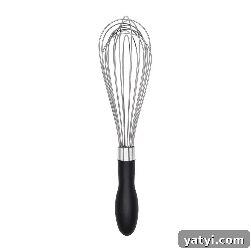 A metal wire whisk with a black handle, designed for mixing or whipping ingredients, is standing upright against a plain white background.