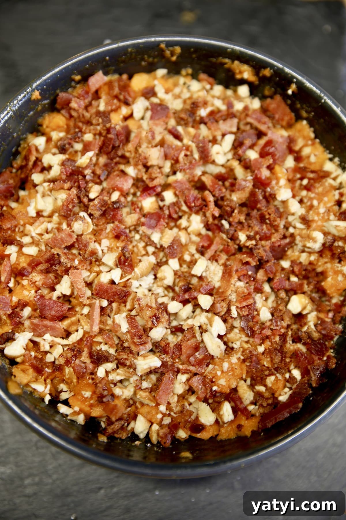 Bacon and pecan topped sweet potato casserole. Bowl of sweet potato casserole with bacon and pecans.