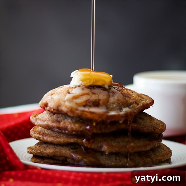 Buttermilk Apple Cinnamon Pancakes with Brown Sugar Glaze 8 Pouring maple syrup over a stack of Apple Cinnamon Pancakes.