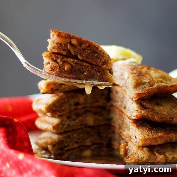 Buttermilk Apple Cinnamon Pancakes with Brown Sugar Glaze 9 Taking a bite of apple cinnamon pancakes with butter and maple syrup.