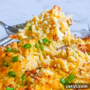 lifting a spoonful of crack potato casserole out of the baking dish.