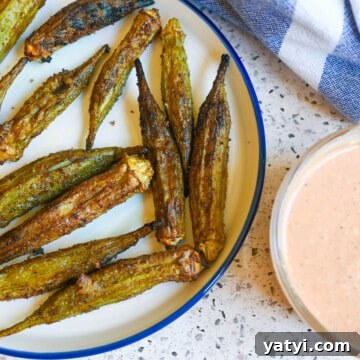 air fryer okra on a plate next to dipping sauce.