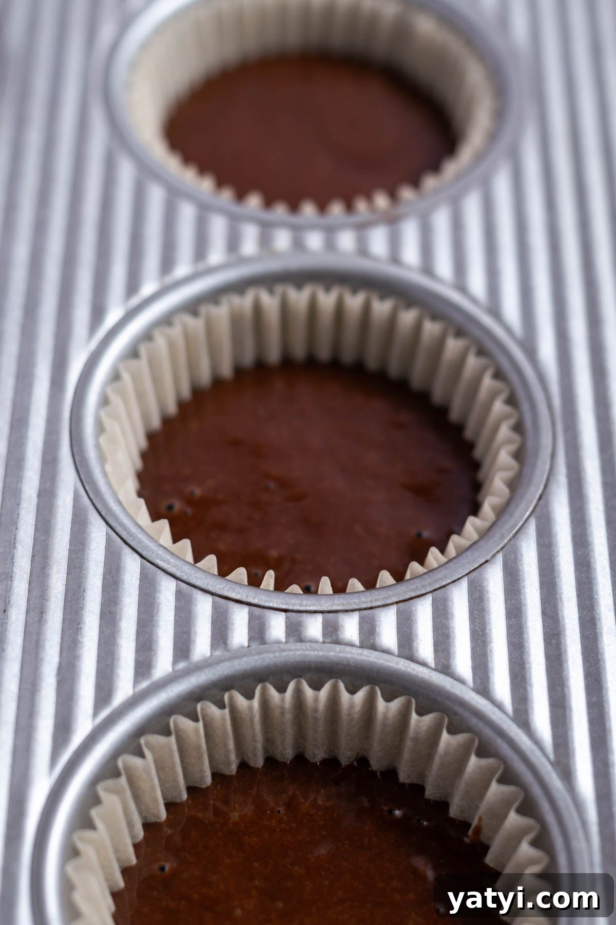 Moist Chocolate Cupcakes with Raspberry Filling and Ganache 13 chocolate cupcake batter half filling liners in a muffin tin