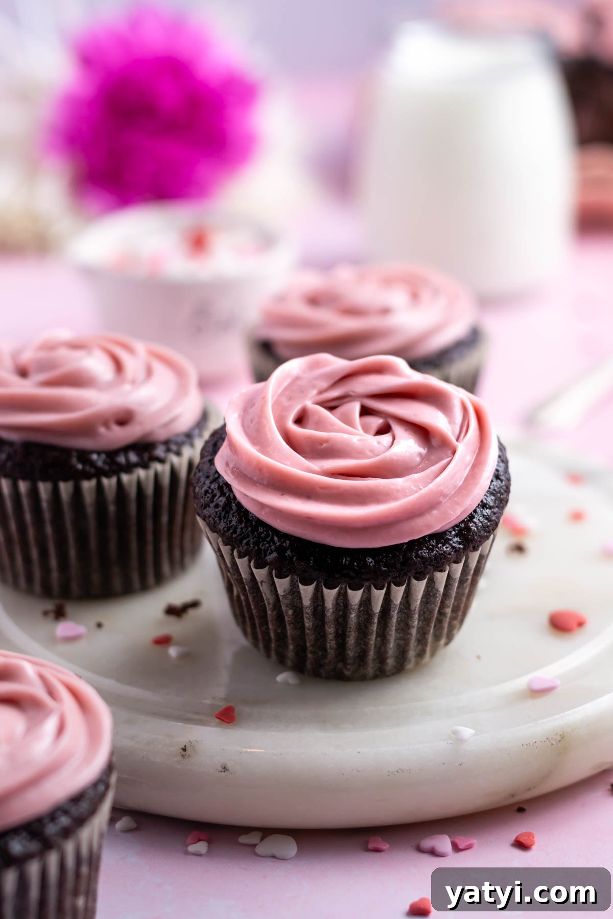 Moist Chocolate Cupcakes with Raspberry Filling and Ganache 18 three chocolate cupcakes on a marble plate with a glass of milk
