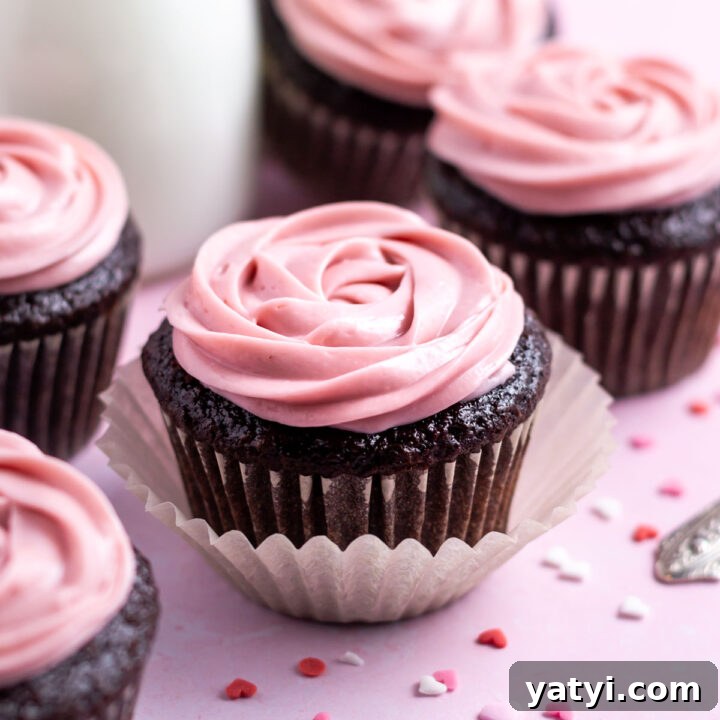chocolate raspberry cupcakes with heart shaped sprinkles and a glass of milk in the background