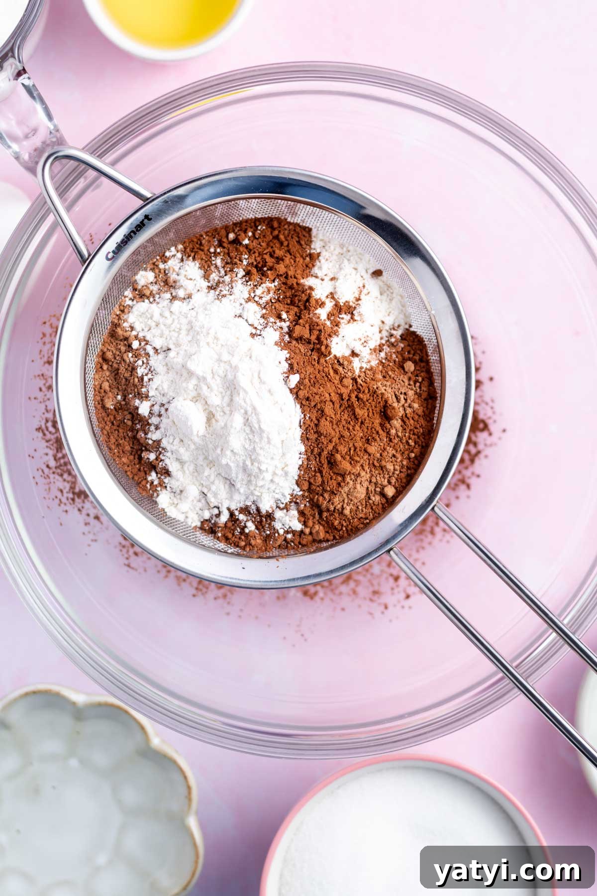 Moist Chocolate Cupcakes with Raspberry Filling and Ganache 9 sifter with flour and cocoa powder sitting over the top of a glass bowl