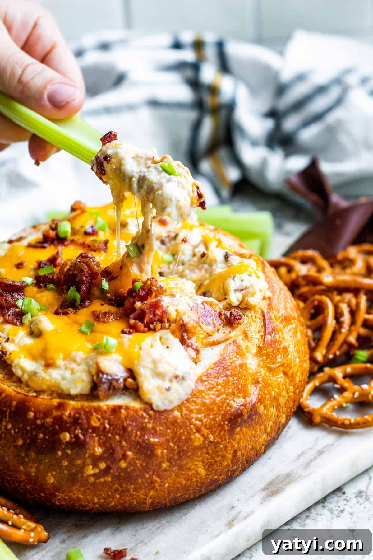 Baked Bacon and Cheese Dip Served in a Warm Bread Bowl 6 Celery being dipped into bacon dip in bread bowl.
