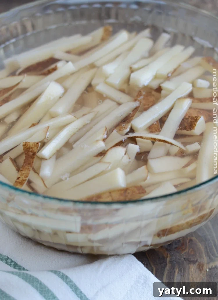 Crispy Oven-Baked French Fries You Can Make at Home 3 baked french fries potatoes in bowl of water
