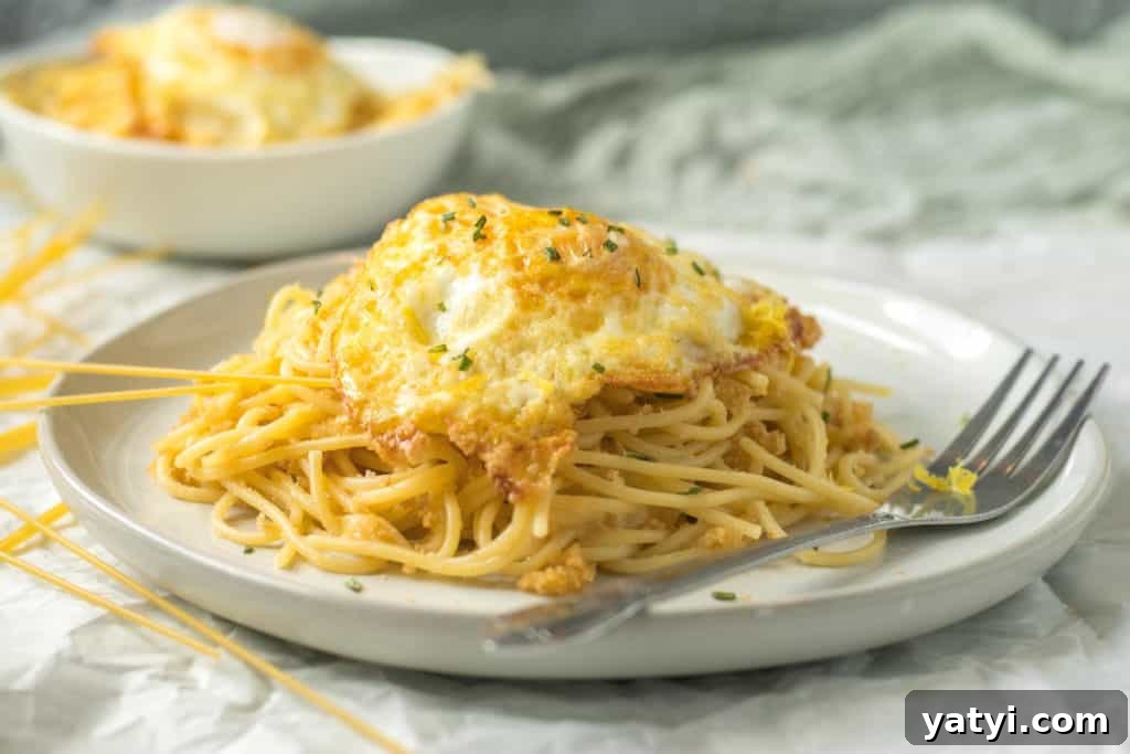 pasta pangrattato on a white plate with a fried egg on top with a fork next to it