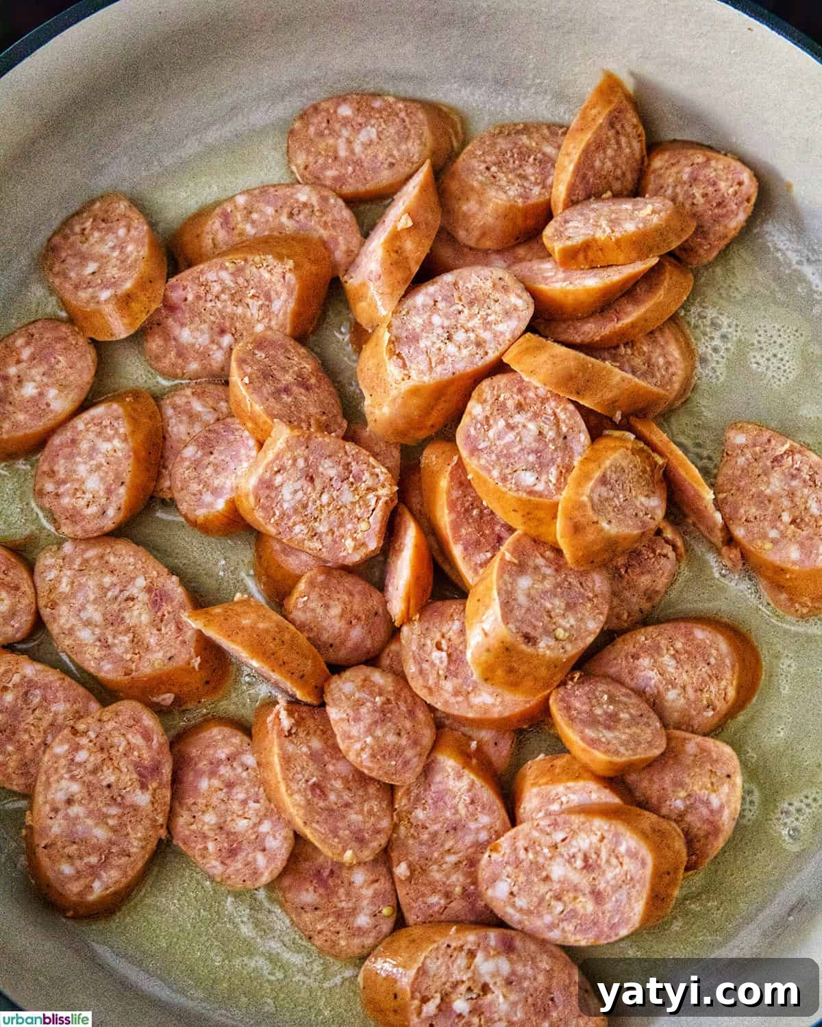 Savory Sausage and Cabbage Skillet Recipe for Weeknight Dinners 7 sliced kielbasa sausage in a skillet cooking.