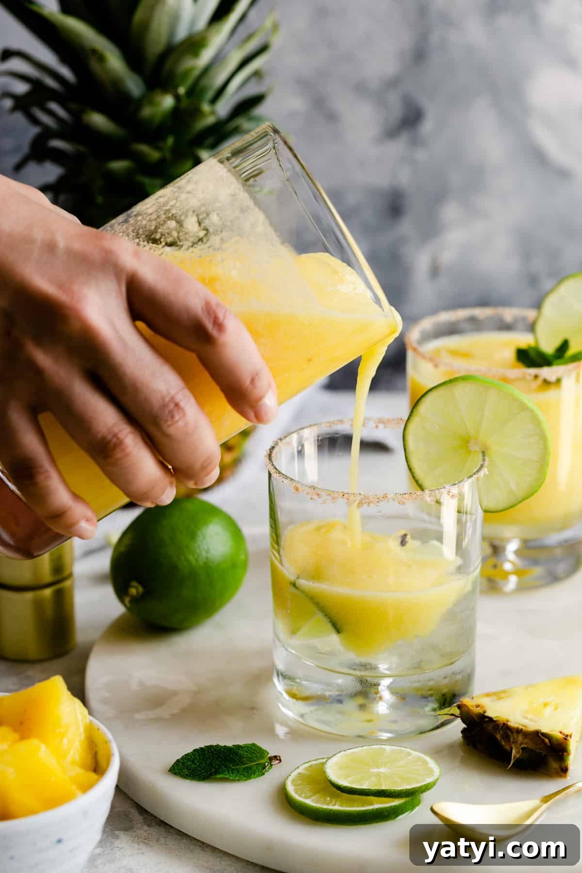 Frozen Pineapple Margarita Recipe — Tropical Cocktail Guide 4 a person pouring a cocktail into a glass