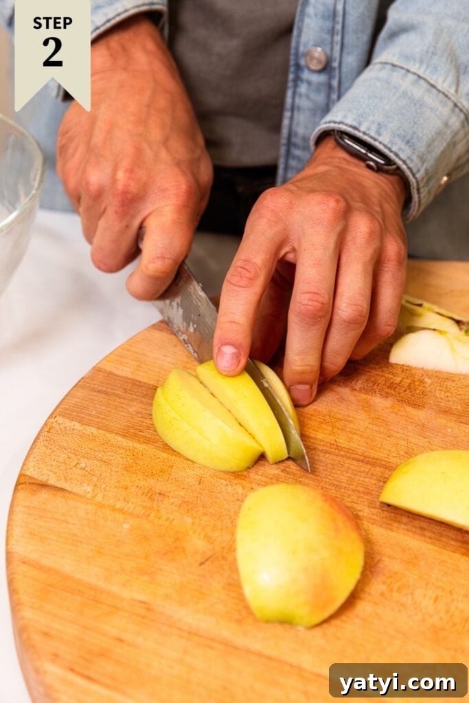 Chewy Cinnamon Apple Pie Bars: Easy Recipe for Fall Baking 11 Two hands using a knife to slice up yellow apples on a wooden cutting board.