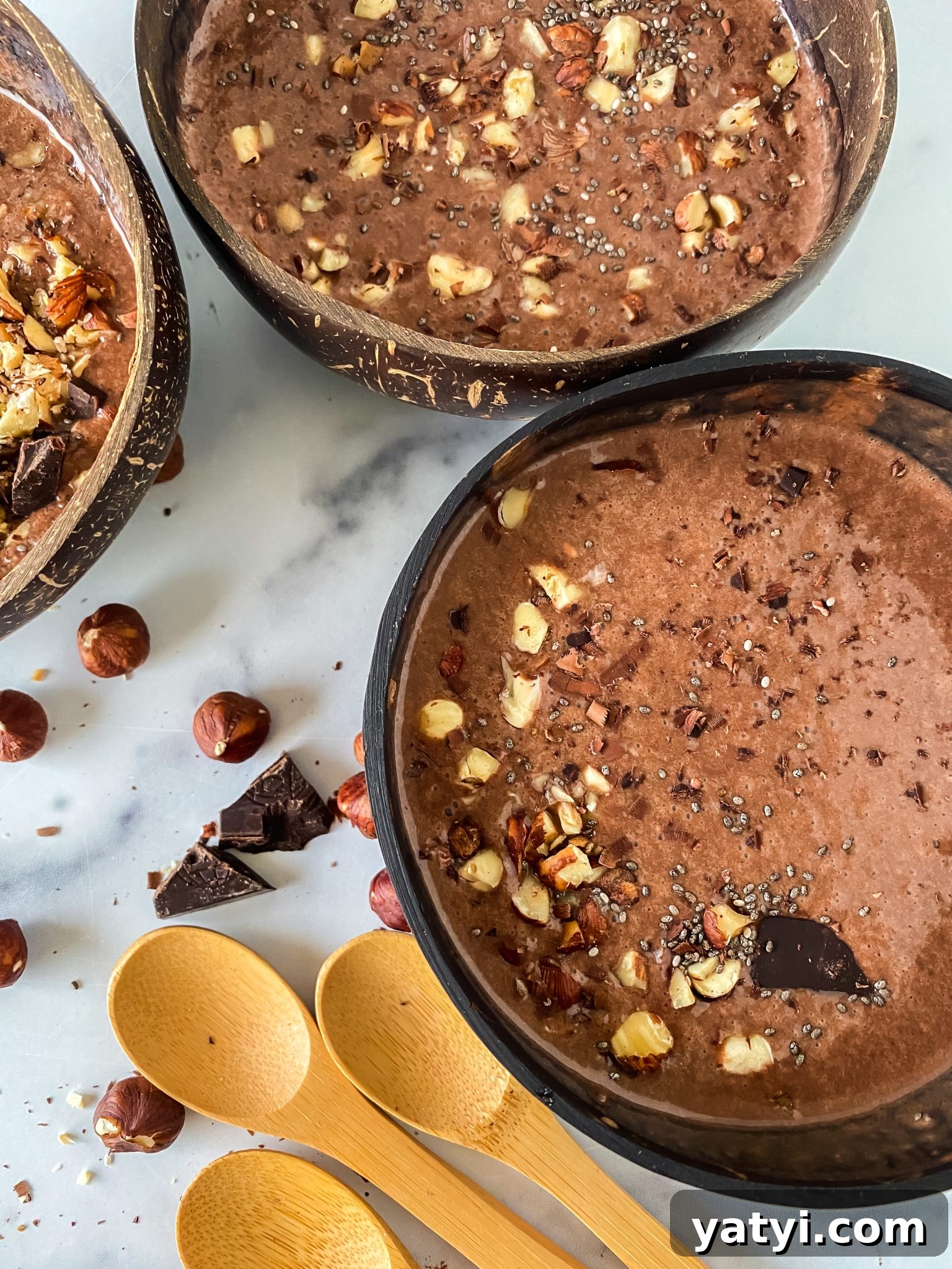 Chocolate Hazelnut Smoothie Bowl: Creamy Breakfast Recipe 2 Top down view of three bowls of Chocolate Hazelnut Smoothies garnished with chopped hazelnuts.