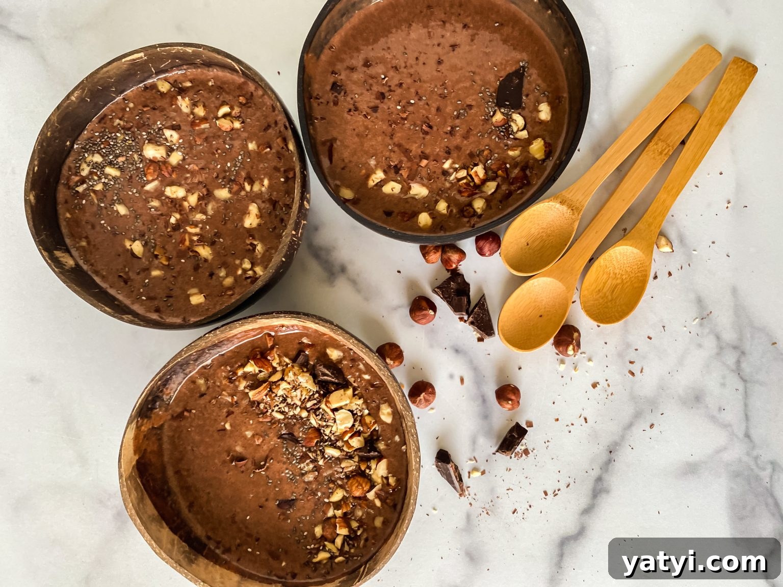 Chocolate Hazelnut Smoothie Bowl: Creamy Breakfast Recipe 5 Top down view of three Chocolate Hazelnut Smoothie Bowls garnished with chopped hazelnuts and chocolate chunks.