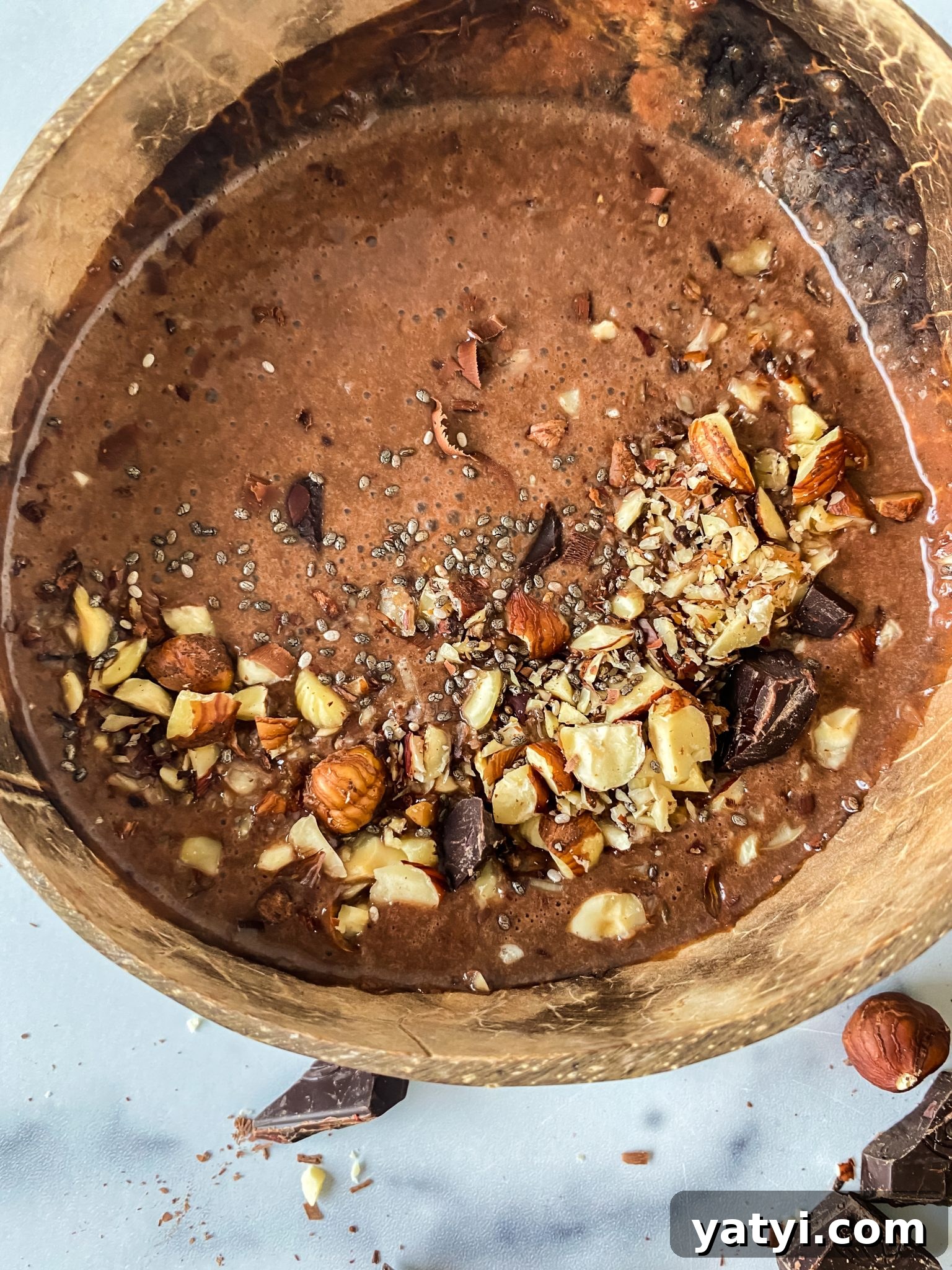 Chocolate Hazelnut Smoothie Bowl: Creamy Breakfast Recipe 6 Banana Nutella Smoothie in a bowl garnished with chopped nuts, seeds, and chocolate chunks.