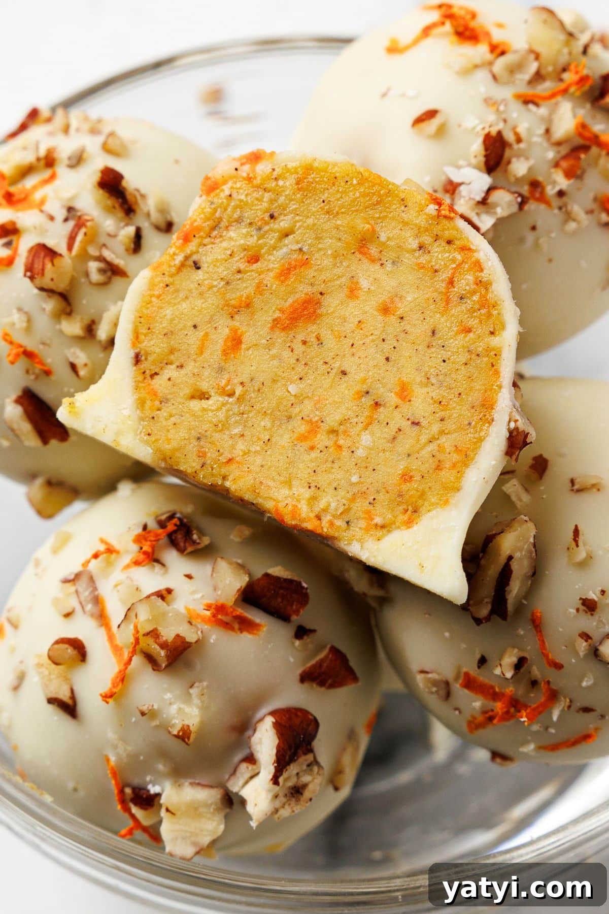 Keto Carrot Cake Protein Bites Recipe for Low-Carb Snacks 2 Keto carrot cake bites coated in white chocolate with pecans and shredded carrots, one bitten in half to show the spiced inside