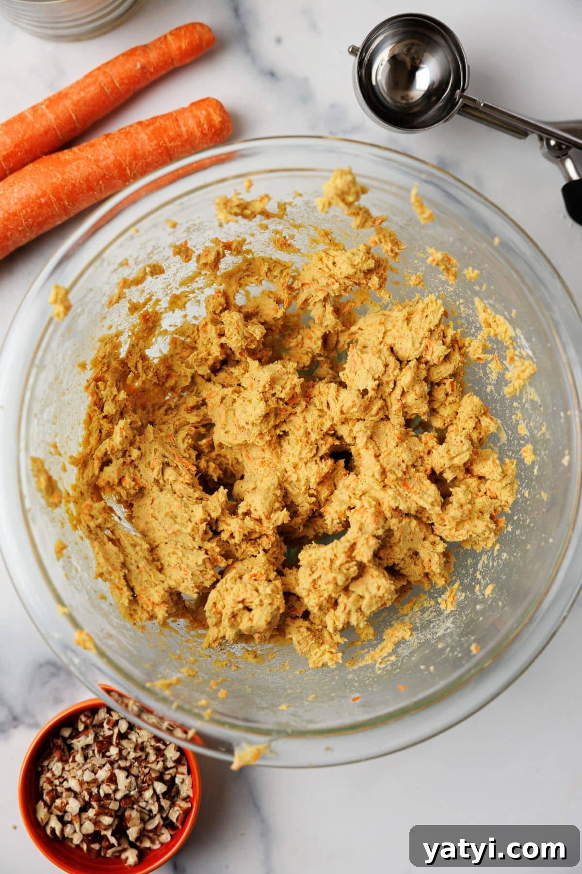 Keto Carrot Cake Protein Bites Recipe for Low-Carb Snacks 5 Thick golden carrot cake mixture in a glass bowl after mixing, with bits of shredded carrot throughout