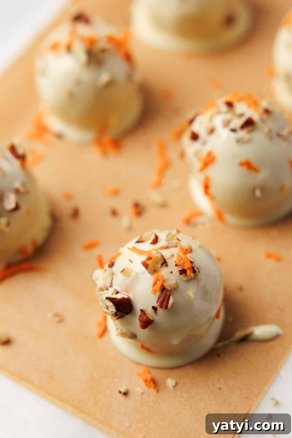 Keto Carrot Cake Protein Bites Recipe for Low-Carb Snacks 10 White chocolate carrot cake bites topped with pecans and shredded carrot arranged on parchment paper to set