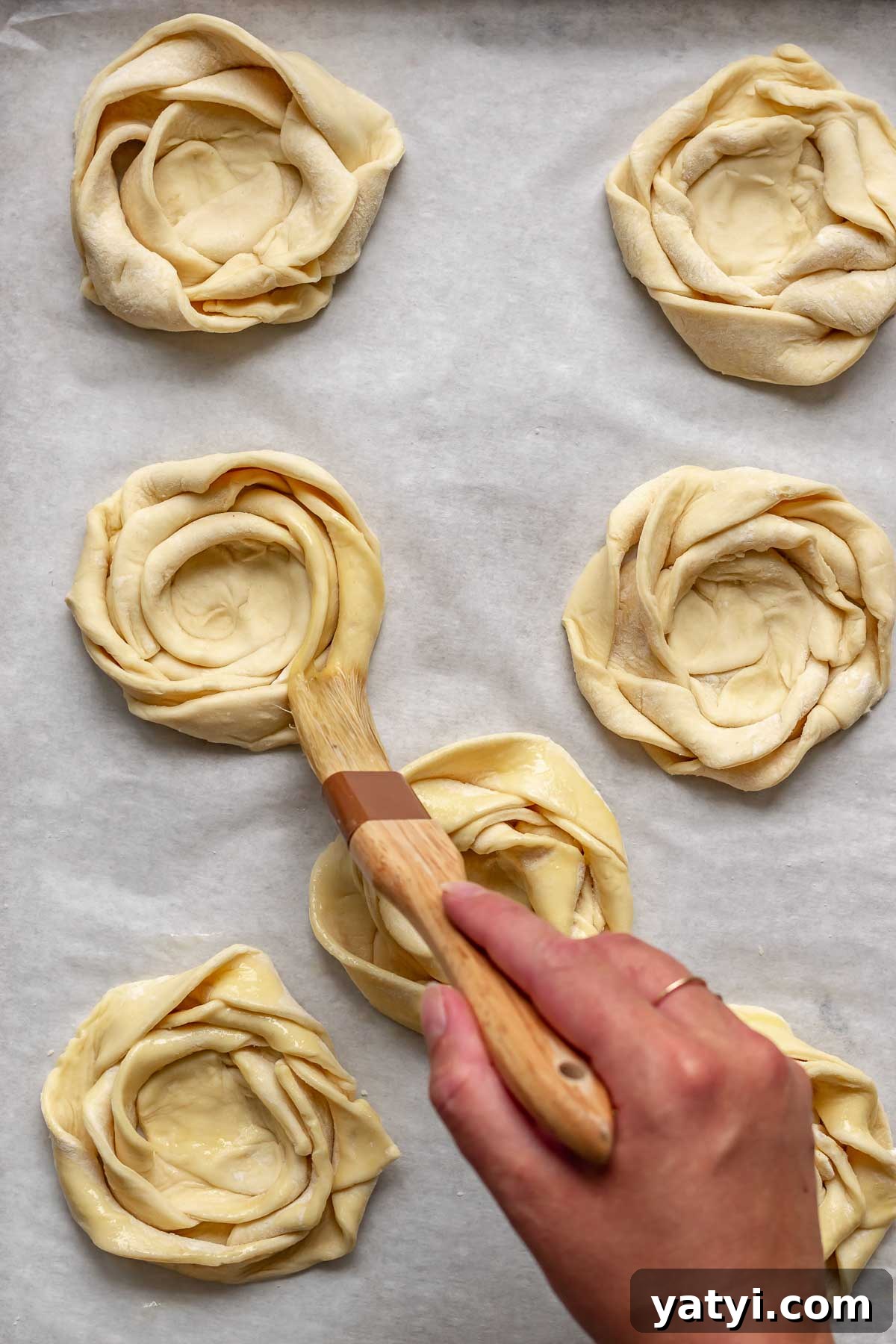 A pastry brush adds egg wash to the puff pastry roses.