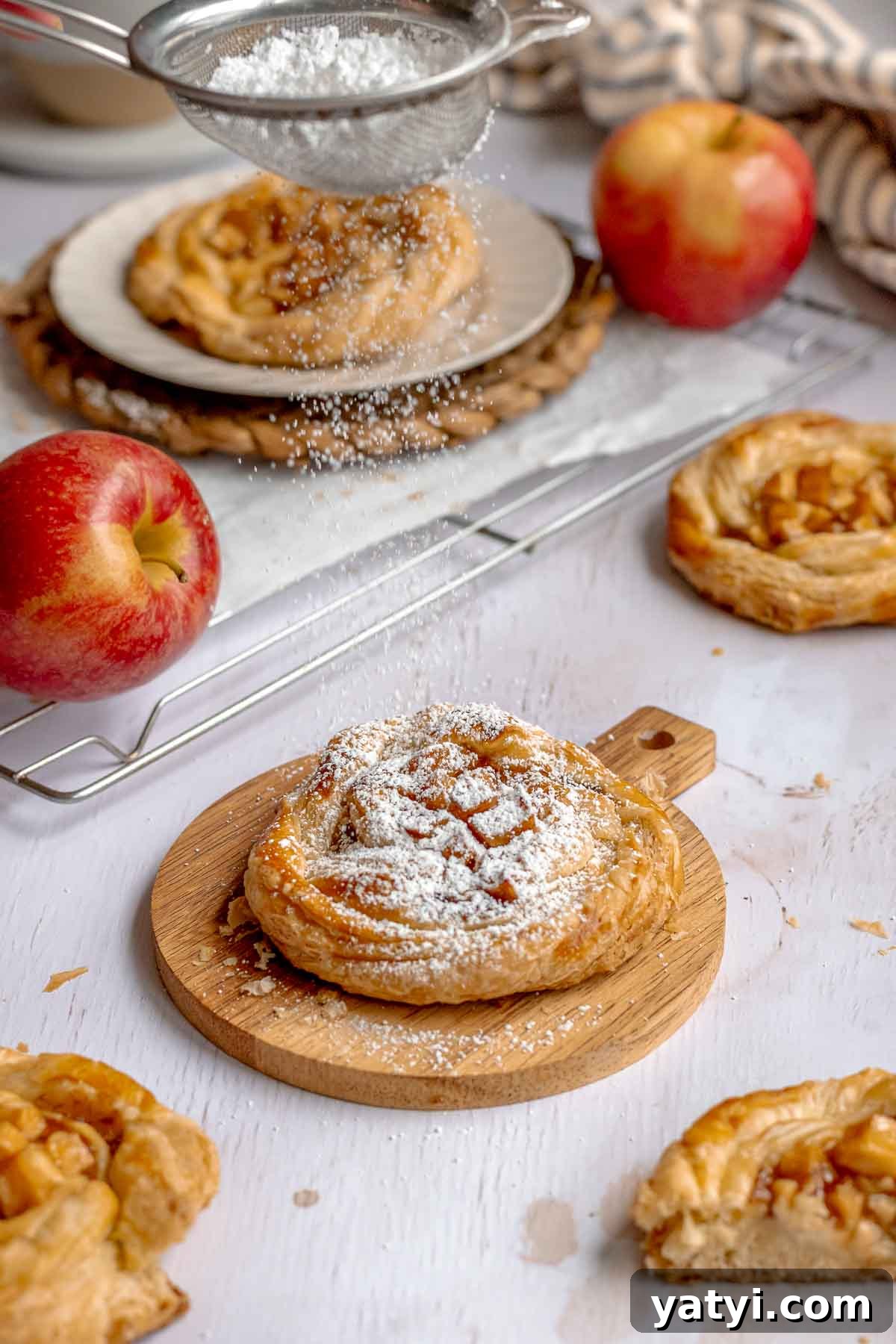 Powdered sugar being dusted on top of an apple danish.