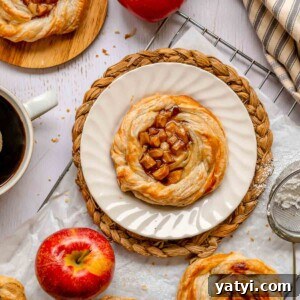 Apple danish on a plate with other pastries scattered around.