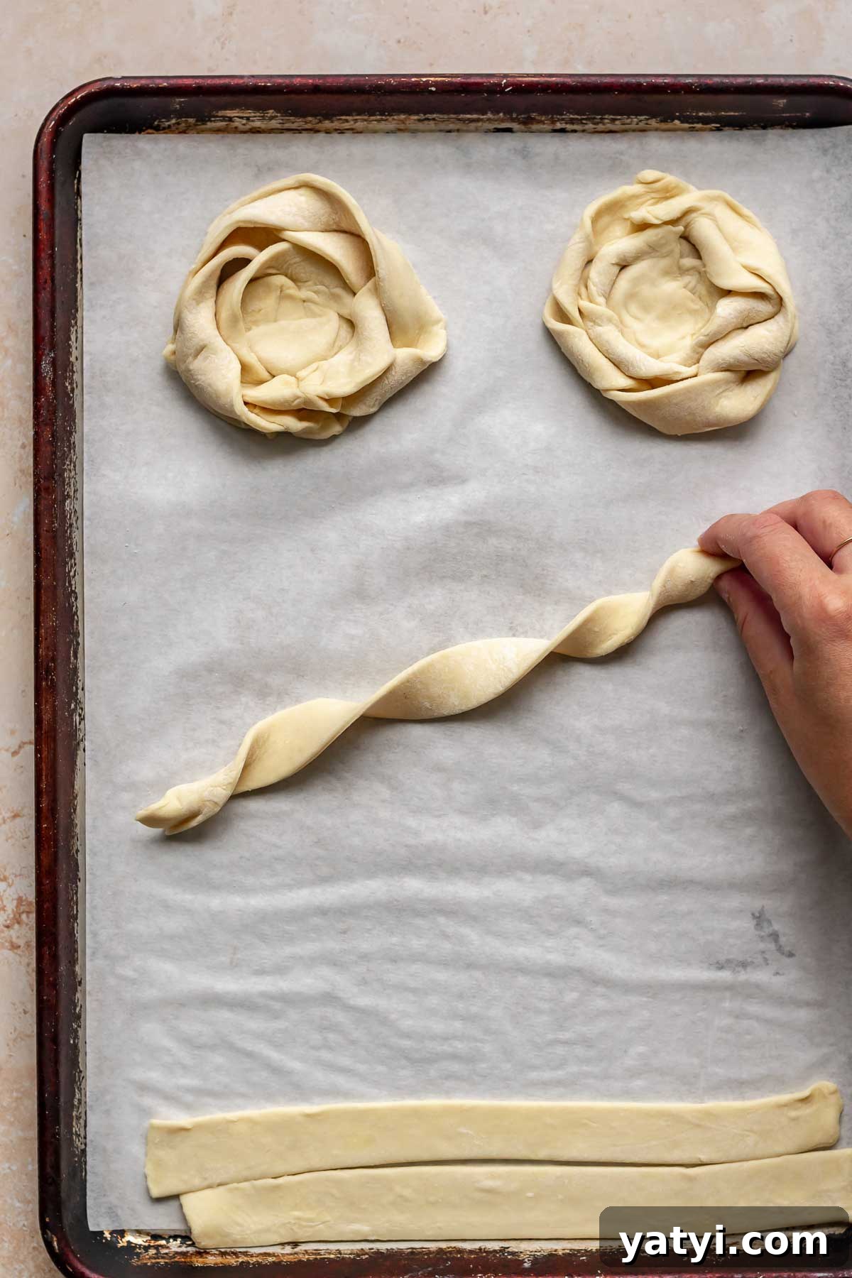 A hand holds a corkscrewed piece of puff pastry.