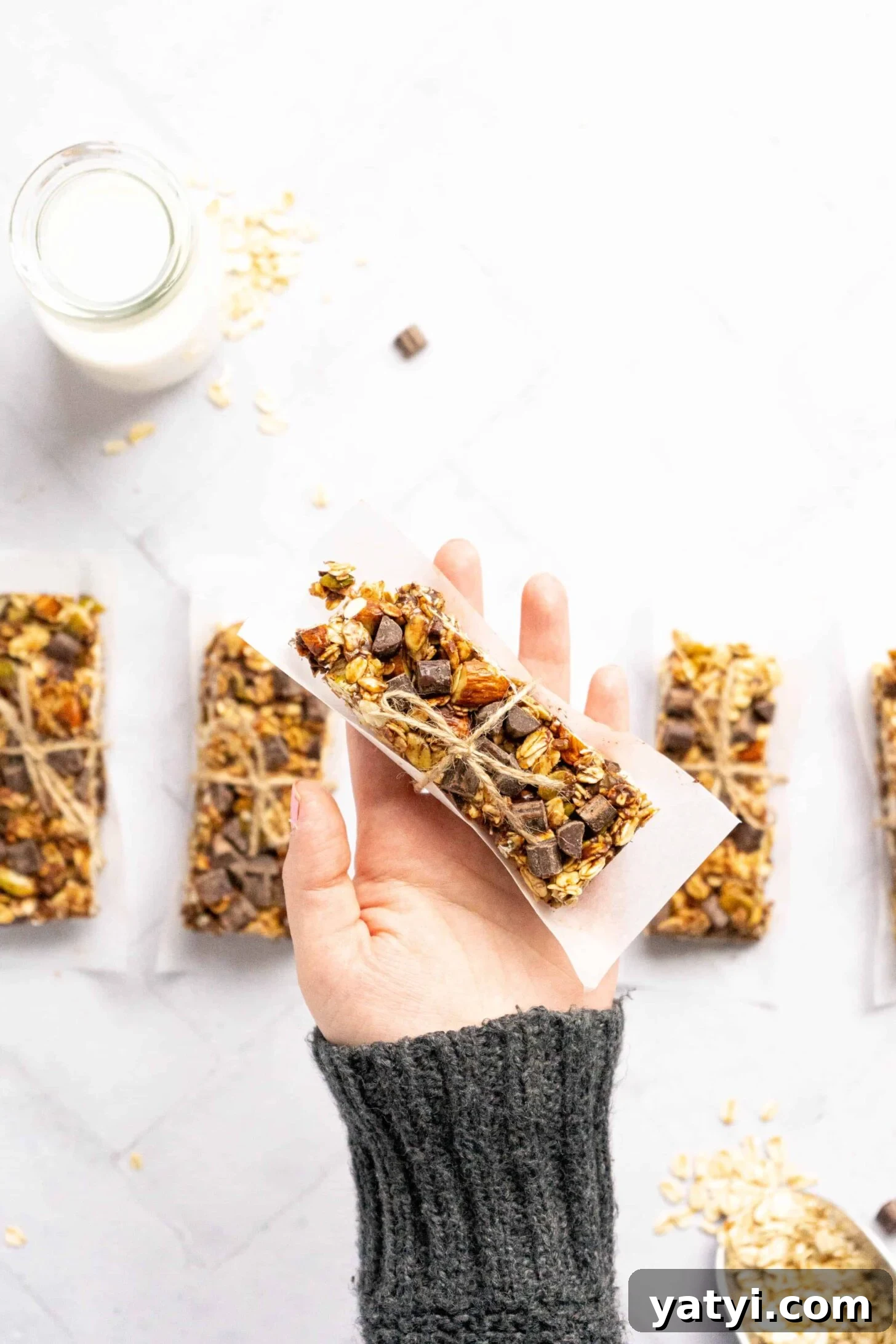 Homemade Gluten-Free Granola Bars with Oats and Almonds 2 A hand holding a granola bar wrapped in parchment paper and twine