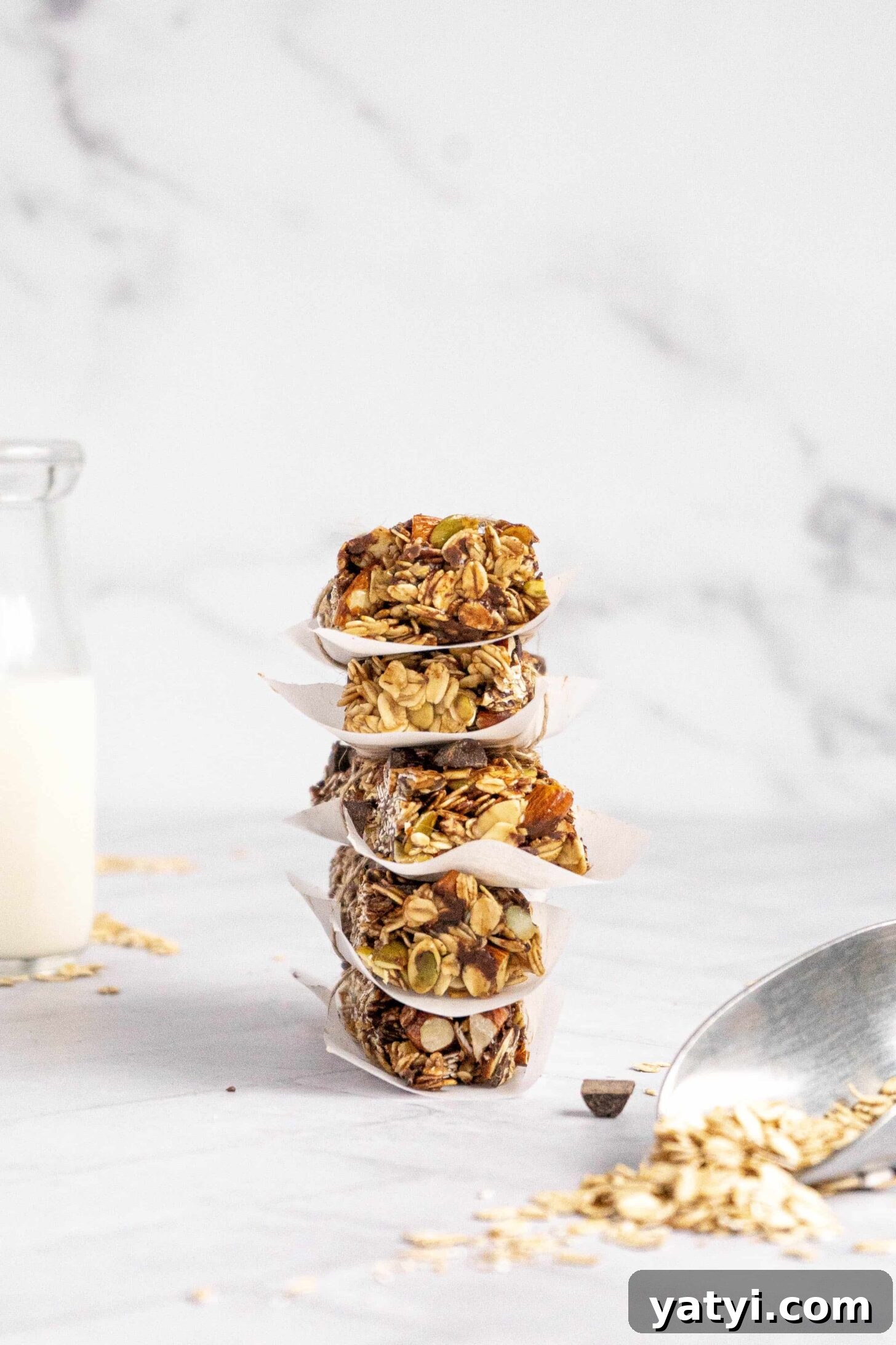 Homemade Gluten-Free Granola Bars with Oats and Almonds 11 A stack of granola bars with parchment paper and a jar of milk