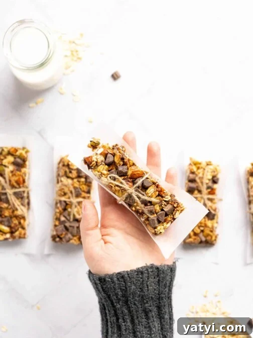 A hand holding a granola bar wrapped in parchment paper and twine