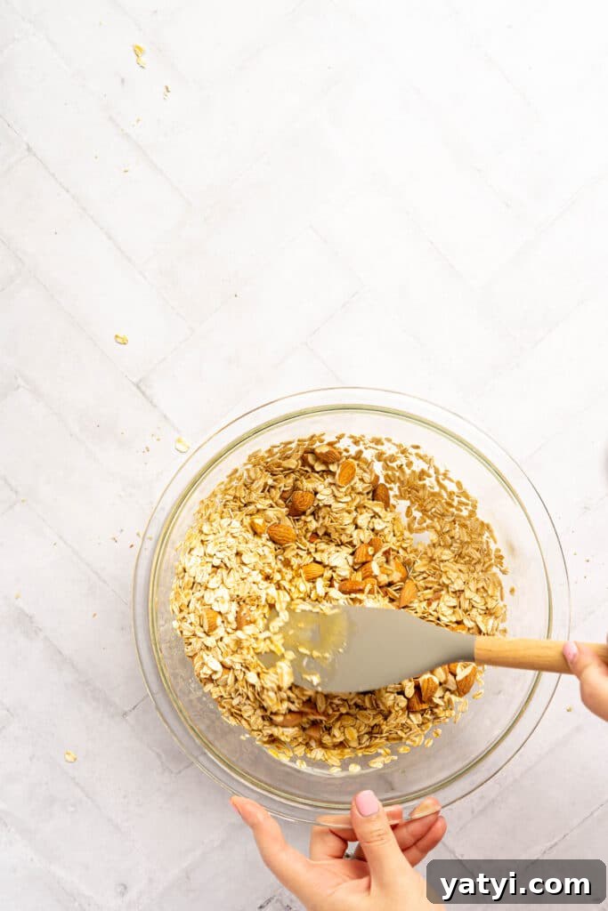 Homemade Gluten-Free Granola Bars with Oats and Almonds 5 Two hands mixing granola in a bowl