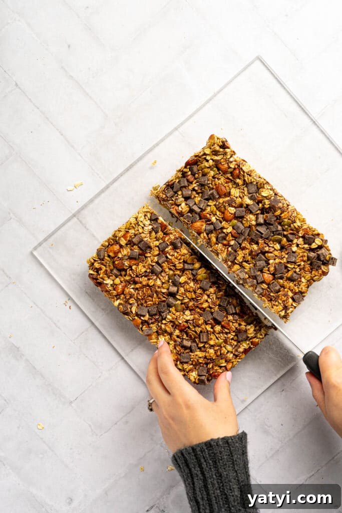 Homemade Gluten-Free Granola Bars with Oats and Almonds 8 Two hands cutting granola bars with a knife