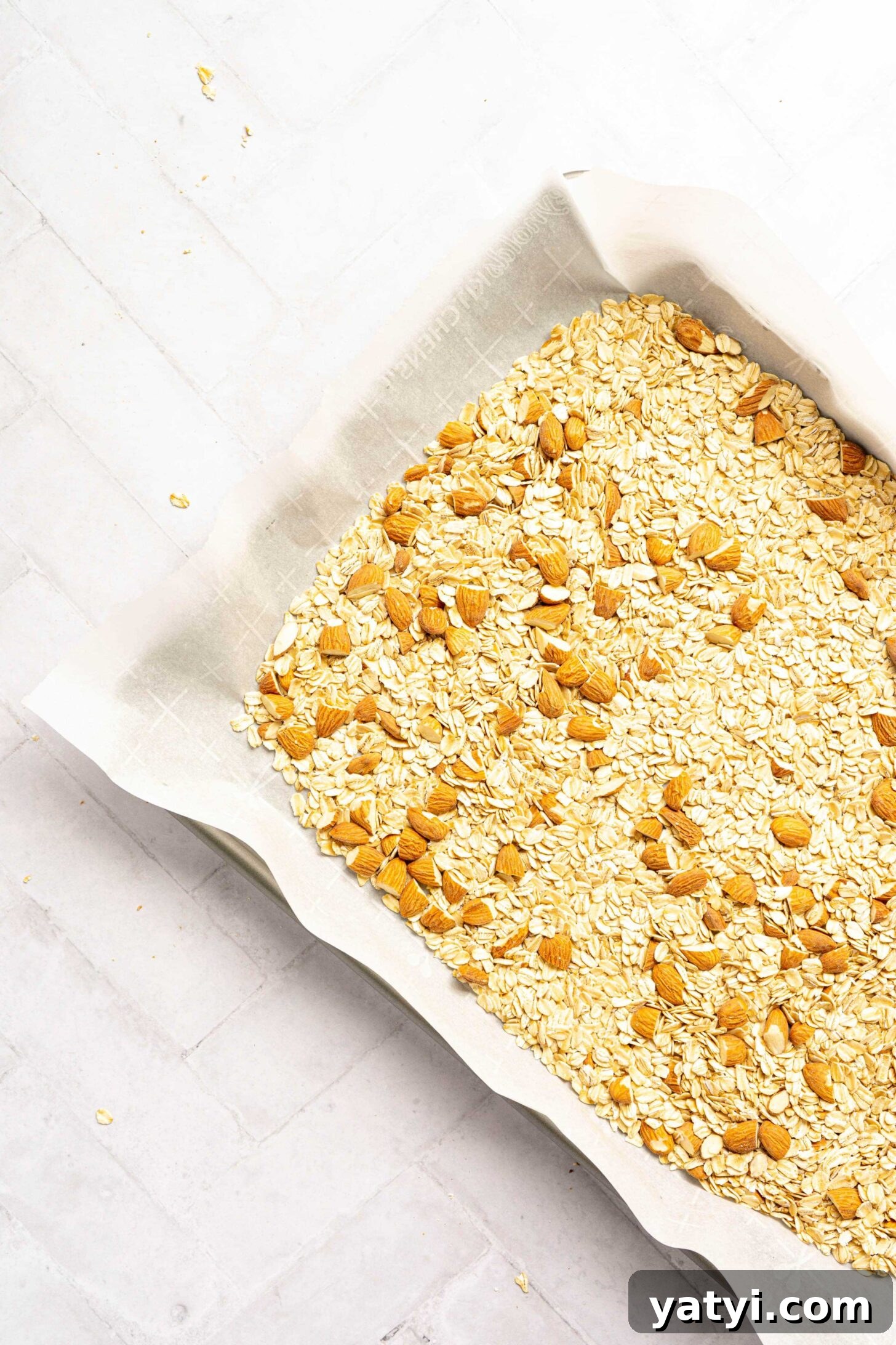 Homemade Gluten-Free Granola Bars with Oats and Almonds 10 A sheet pan with oats and almonds on parchment paper