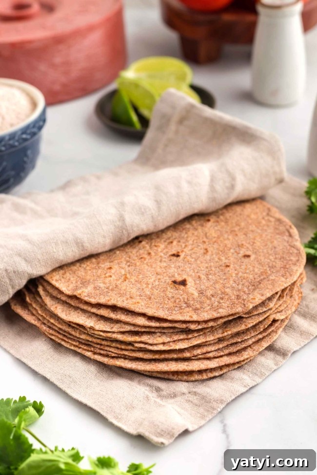 Homemade Whole Wheat Tortillas: Soft, Flexible Wraps Recipe 6 tortillas wrapped in a beige cloth on a white table