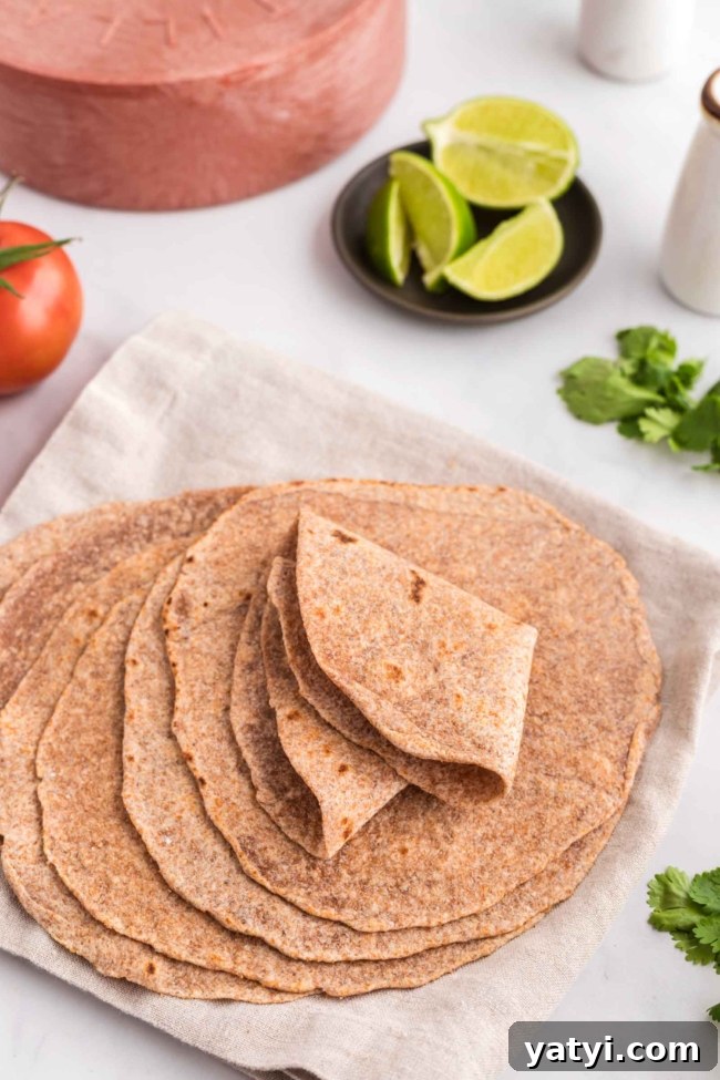 Homemade Whole Wheat Tortillas: Soft, Flexible Wraps Recipe 7 stack of whole wheat tortillas folded in a way to show how pliable they are, on a white table