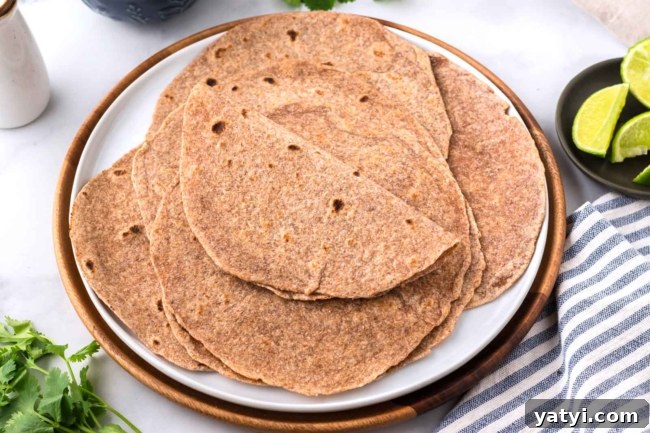 Homemade Whole Wheat Tortillas: Soft, Flexible Wraps Recipe 8 stack of whole wheat tortillas on a white plate with a napkin under plate