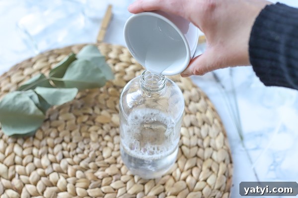 DIY All-Purpose Cleaner That Cleans Glass and Surfaces 4 adding dish soap to glass bottle of vinegar to make homemade cleaning spray