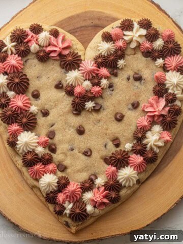 Frosted heart shaped cookie cake on wood platter.
