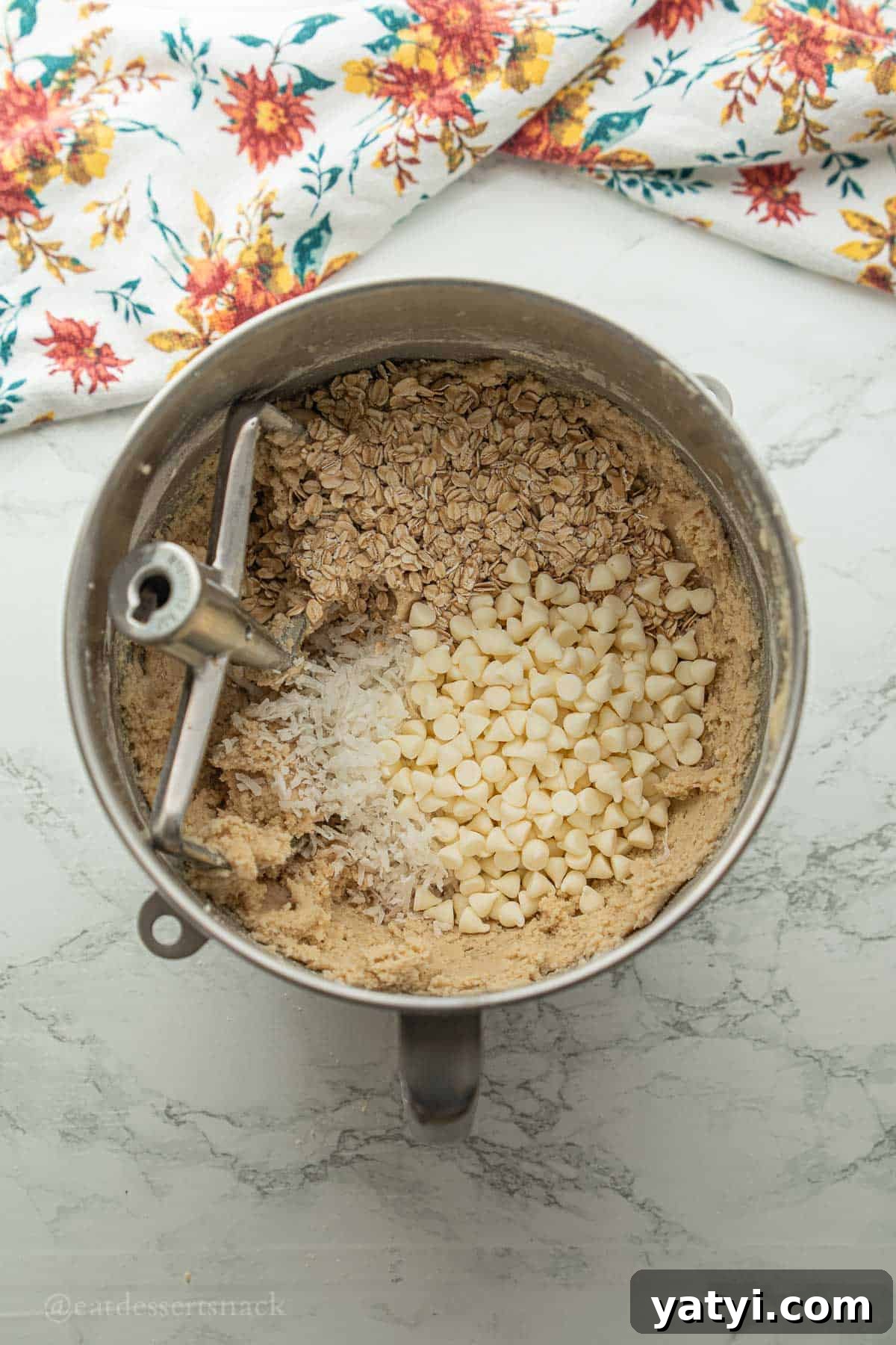 White chocolate chips with oats and coconut in mixing bowl.