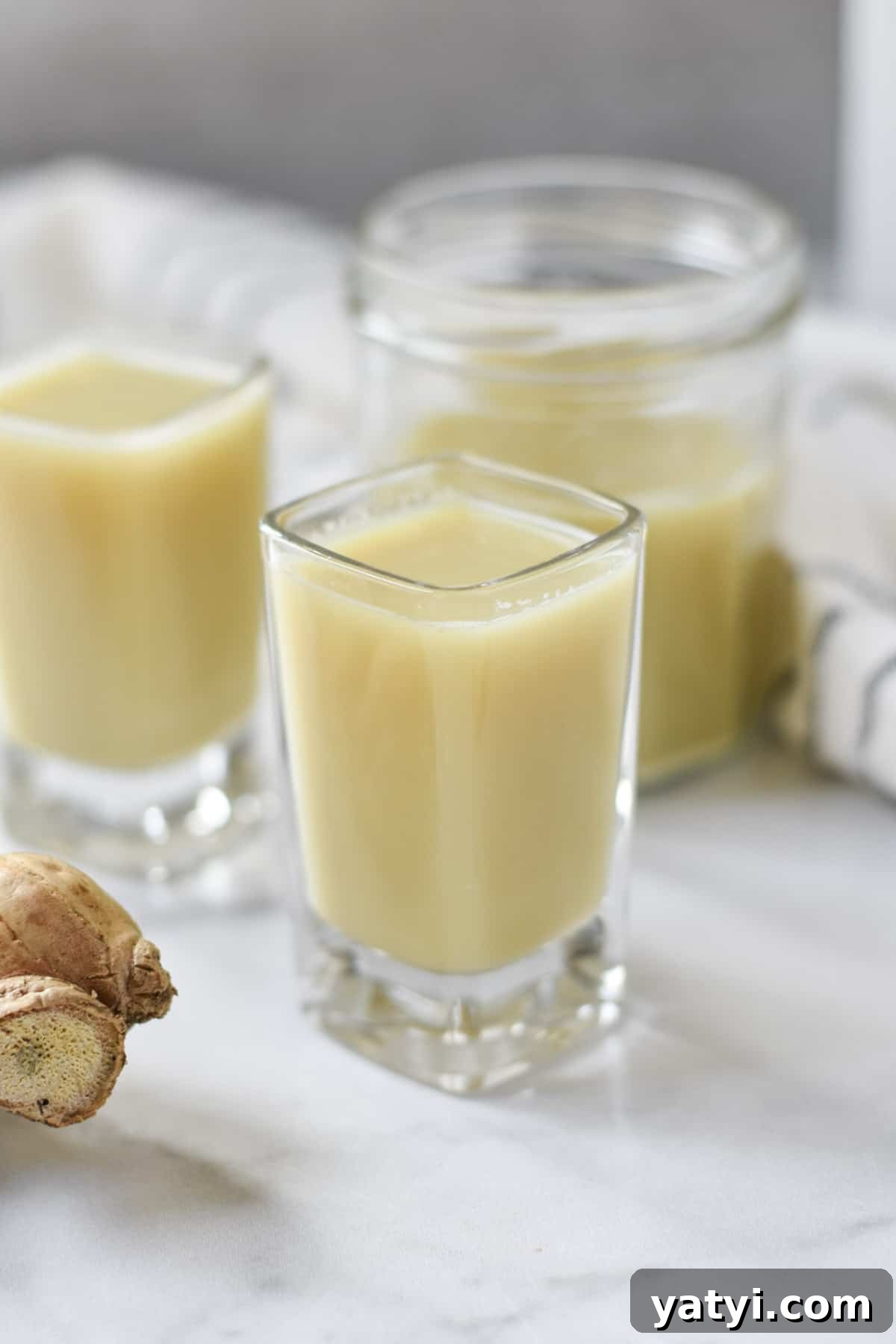 Ginger Juice Recipe: Make Fresh Ginger Juice with a Blender or Juicer 7 Cups with ginger juice next to a fresh ginger root.