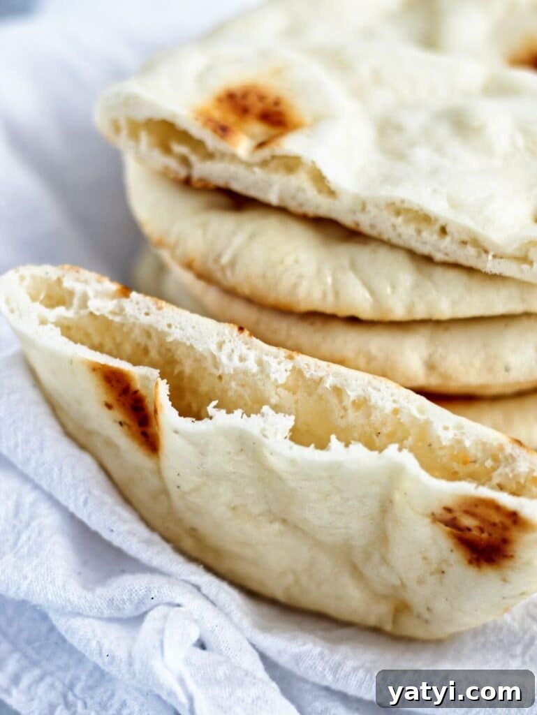 Gluten-Free Pita Bread Recipe: Soft, Flavorful, and Simple 2 stack of gf pita bread on white towel with one cut in half to show pocket.