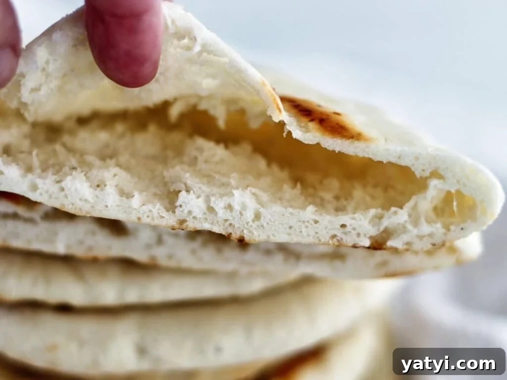 Gluten-Free Pita Bread Recipe: Soft, Flavorful, and Simple 8 showing inside of cut open pita pocket on top of stack of pitas.