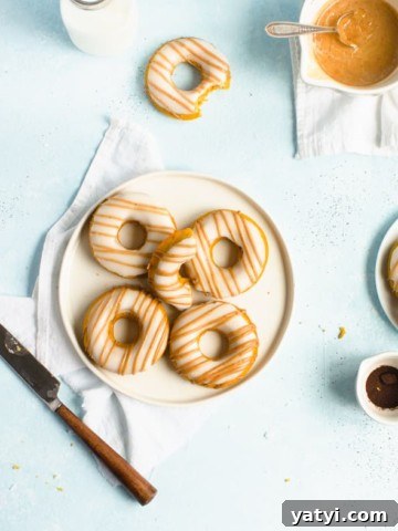 Plate of doughnuts on a white napkin with a knife, jar of milk and bowl of glaze around it