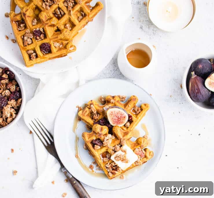 Fluffy Buttermilk Pumpkin Waffles Recipe for Fall Breakfast 7 two triangles of waffles on a blue plate topped with a square of butter, a halved fig and granola.