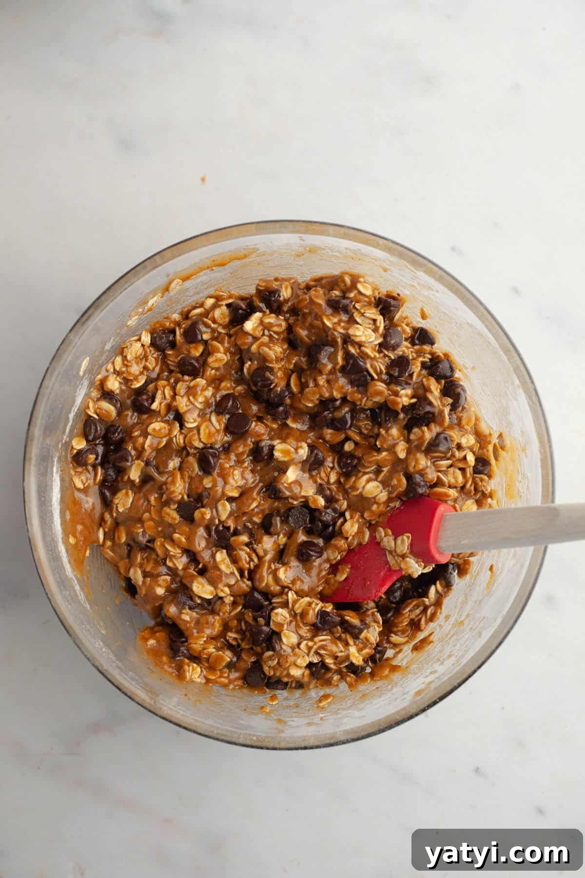 Chewy Brown-Butter Oatmeal Cookies with Chocolate Chips 8 A glass bowl with oatmeal chocolate chip cookie dough.