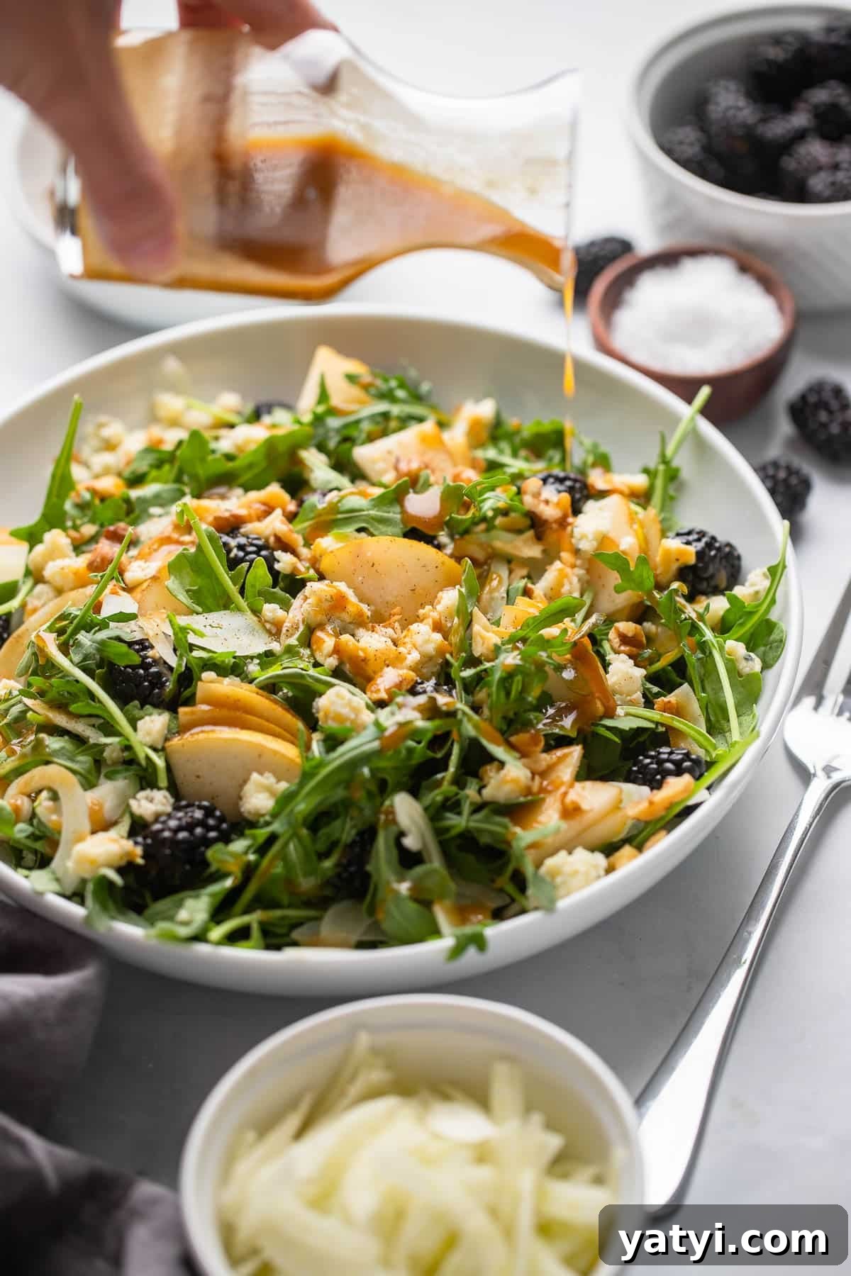 Pear, Walnut and Gorgonzola Salad with Honey-Balsamic Dressing 3 salad dressing being poured onto a pear arugula salad.