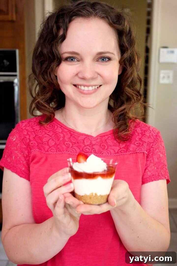 No-Bake Strawberry Cheesecake Cups with Graham Cracker Crust 11 Kelsey Smith holding a strawberry cheesecake cup.