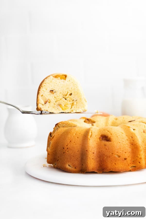Glazed Peach Bundt Cake Recipe with Fresh Summer Peaches 2 Peach Bundt Cake with a sliced being lifted out of the cake.
